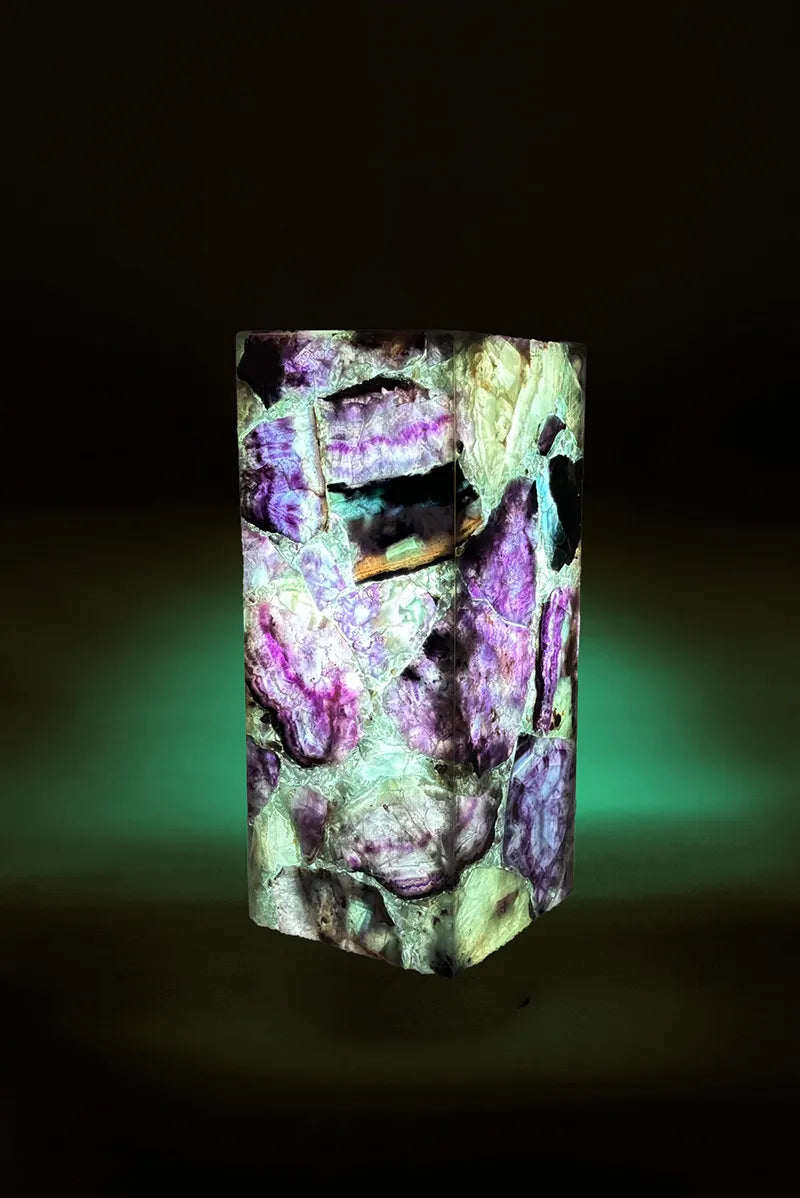 A square-shaped table lamp with a multicolored, solid pattern, likely made of fluorite, glowing with a soft light.