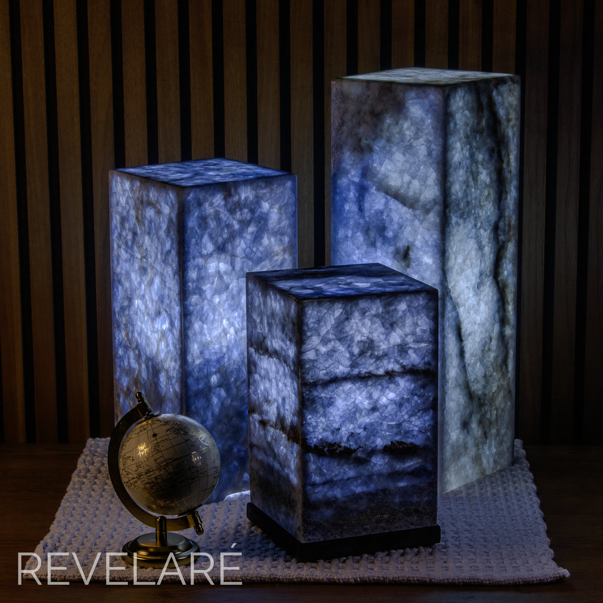 Square blue calcite lamps when lit in a dark room. Comparison of available sizes.